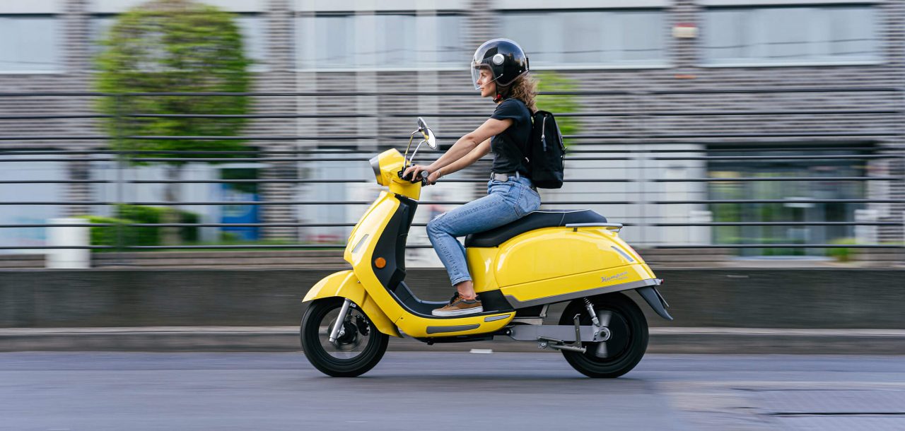 Elektroroller Moped in gelb von Kumpan mit junger Frau